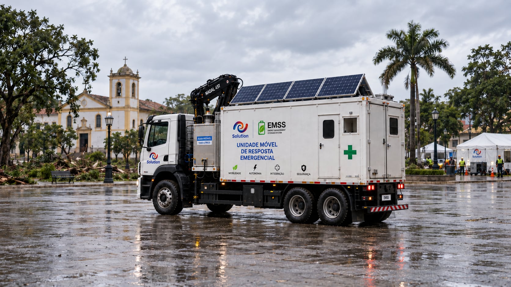 Caminhão da unidade móvel EMSS Solution com munck, reservatório de água e painéis solares, estacionado numa praça durante o dia, com tendas de atendimento ao fundo.